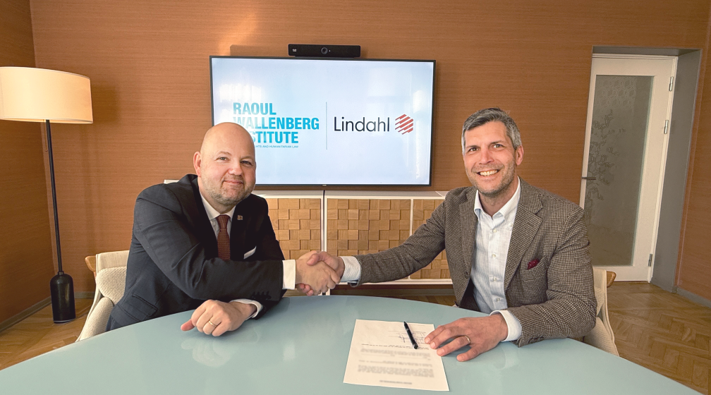 Två leende män som signerar ett kontrakt och skakar hand