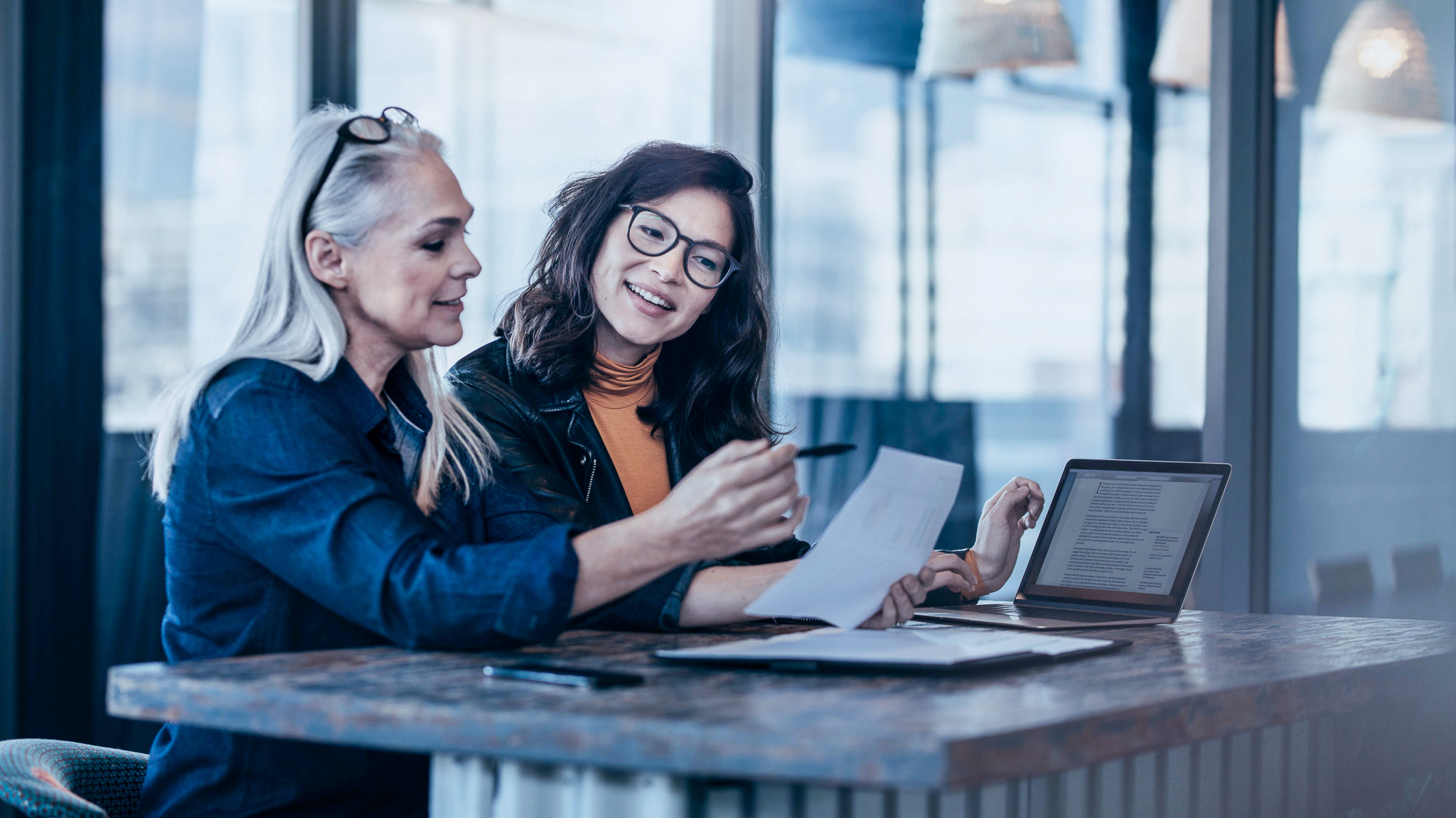 Två kvinnor tittar på ett papper och diskuterar