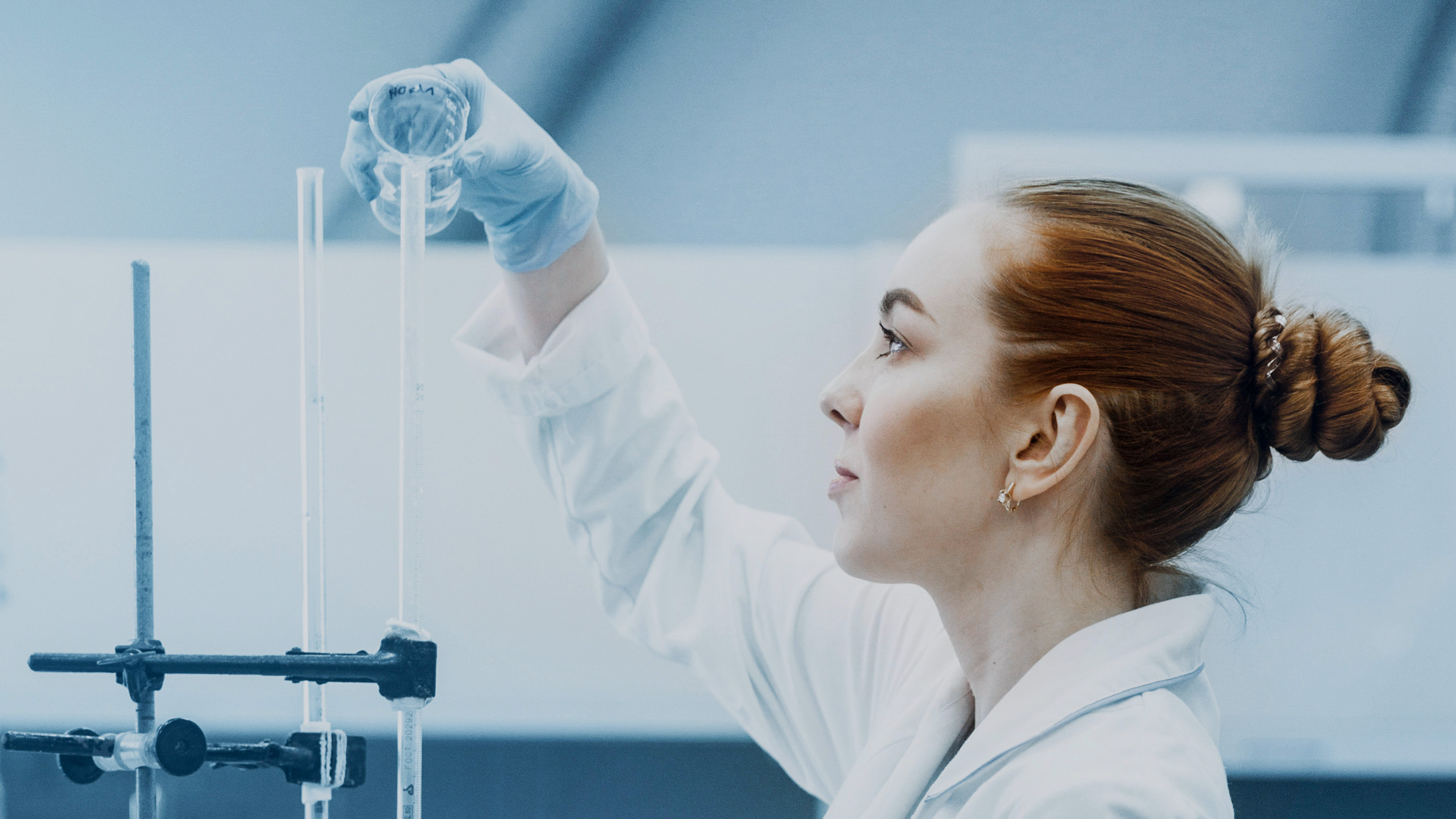 Kvinna i labbrock häller något i mätrör